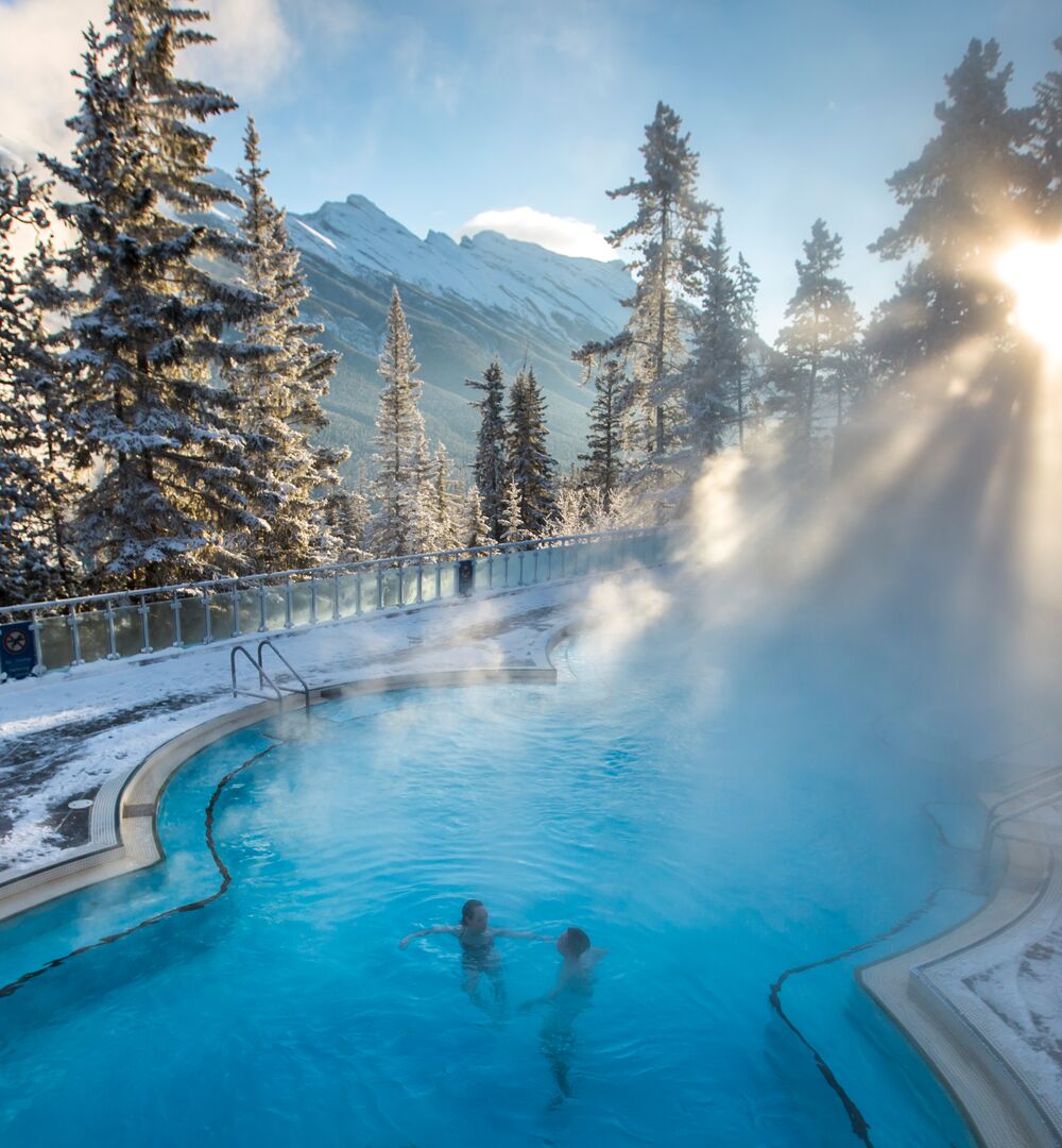 Two people soaking in the Banff Upper Hot Springs on a winters day